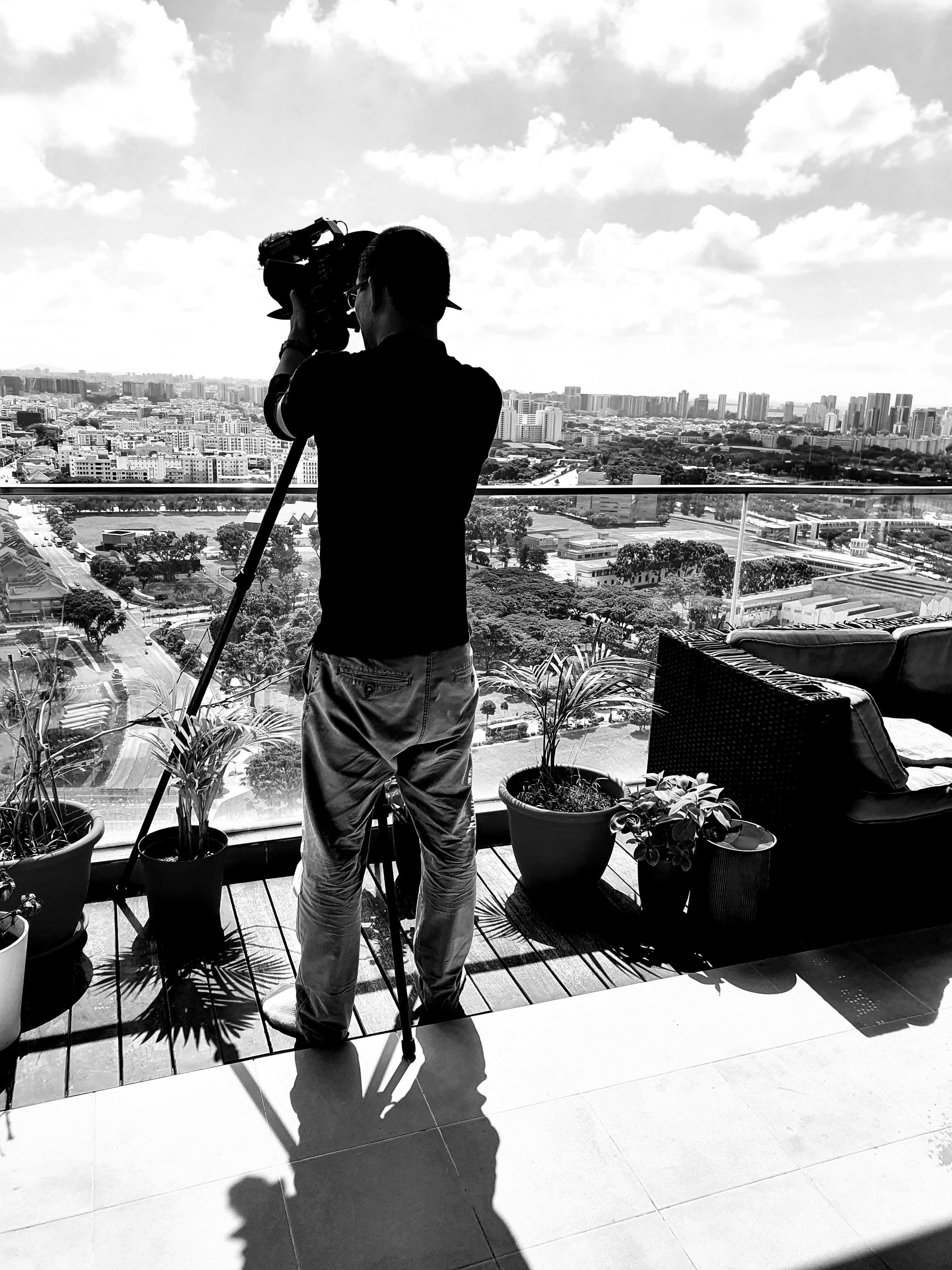 man in black polo shirt wearing white mask holding black camera