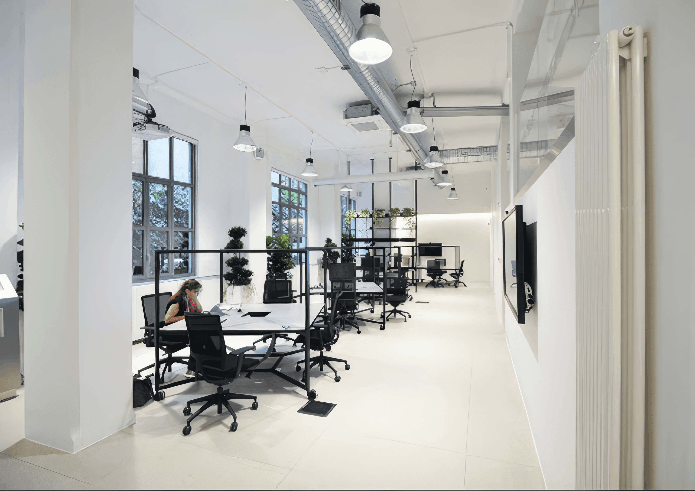 MW Interior  - Seitenansicht eines modernen Loft-Büros mit Mitarbeiterin am Arbeitsplatz, schwarzen Stahlrahmentischen, Industrieleuchten und freigeführten Lüftungsrohren" Beschreibung: Lebendige Arbeitsatmosphäre im Loft-Büro: Eine Mitarbeiterin konzentriert an ihrem Arbeitsplatz, umgeben von klarer Schwarz-Weiß-Möblierung, sichtbaren Installationen unter der Decke und gezielter Begrünung als Raumgliederung.