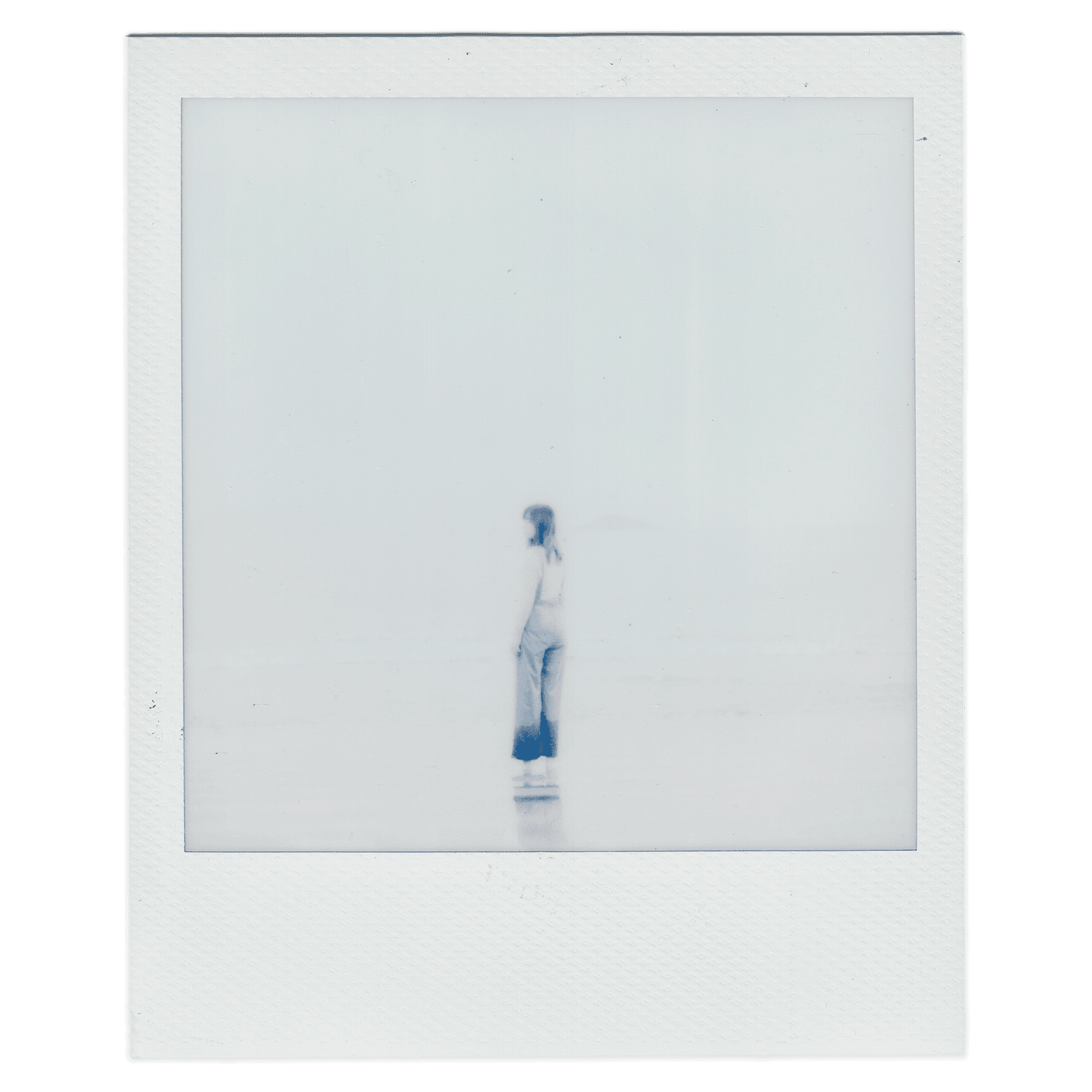 a polaroid that alice is standing in the middle of the beach