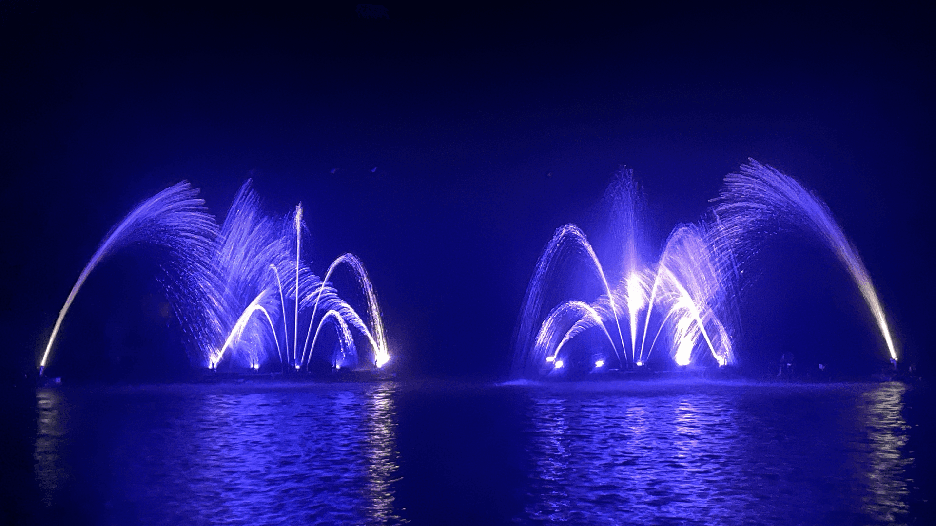 Petits jets d'eau en forme de palmier avec un éclairage bleu sur un lac