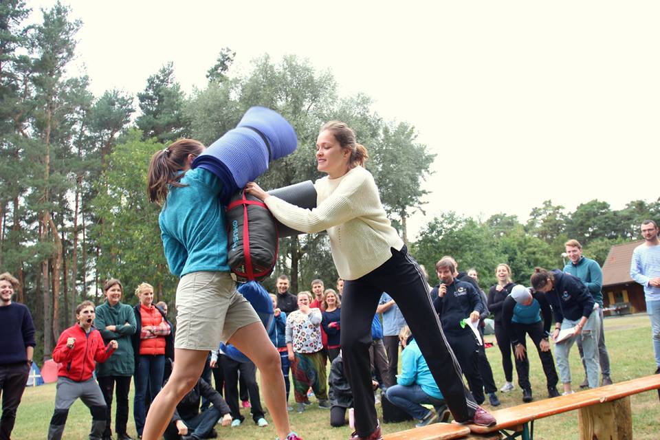 Zwei junge Frauen, die an einem Sportwettbewerb teilnehmen, umgeben von Gemeindemitgliedern, die sich im Kreis versammelt haben und sie anfeuern.