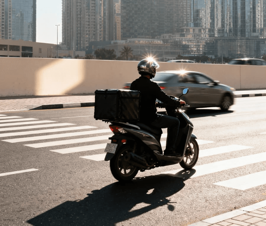 Kurierfahrer auf Roller liefert Essen. Schnelle Essenslieferung in der Stadt. Online bestellen.