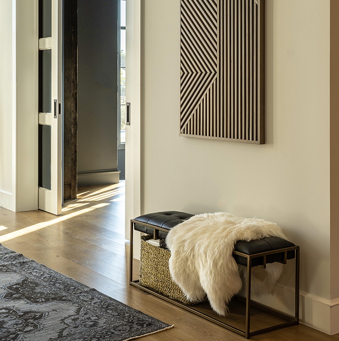 Elegant crystal chandelier with gold frame in luxury primary suite bathroom featuring geometric tile wall design