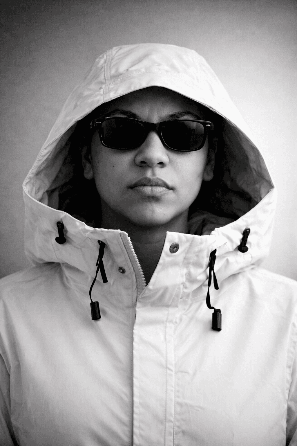 Person wearing a white hooded winter jacket looking directly at the camera against a neutral background.