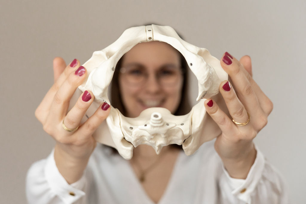 Smiling female therapist with short gray hair, wearing a brown top and a purple shawl, surrounded by a cozy background.