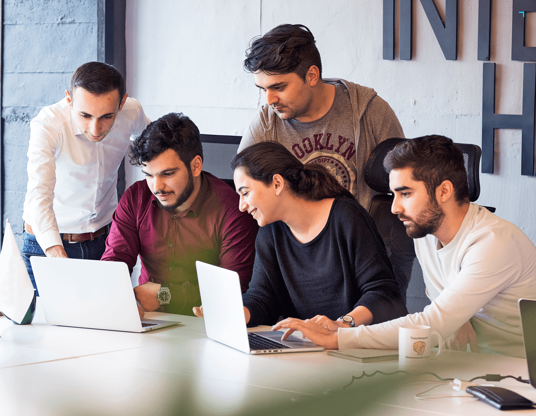 Black and white photo of two people looking at a computer screen with papers on wall