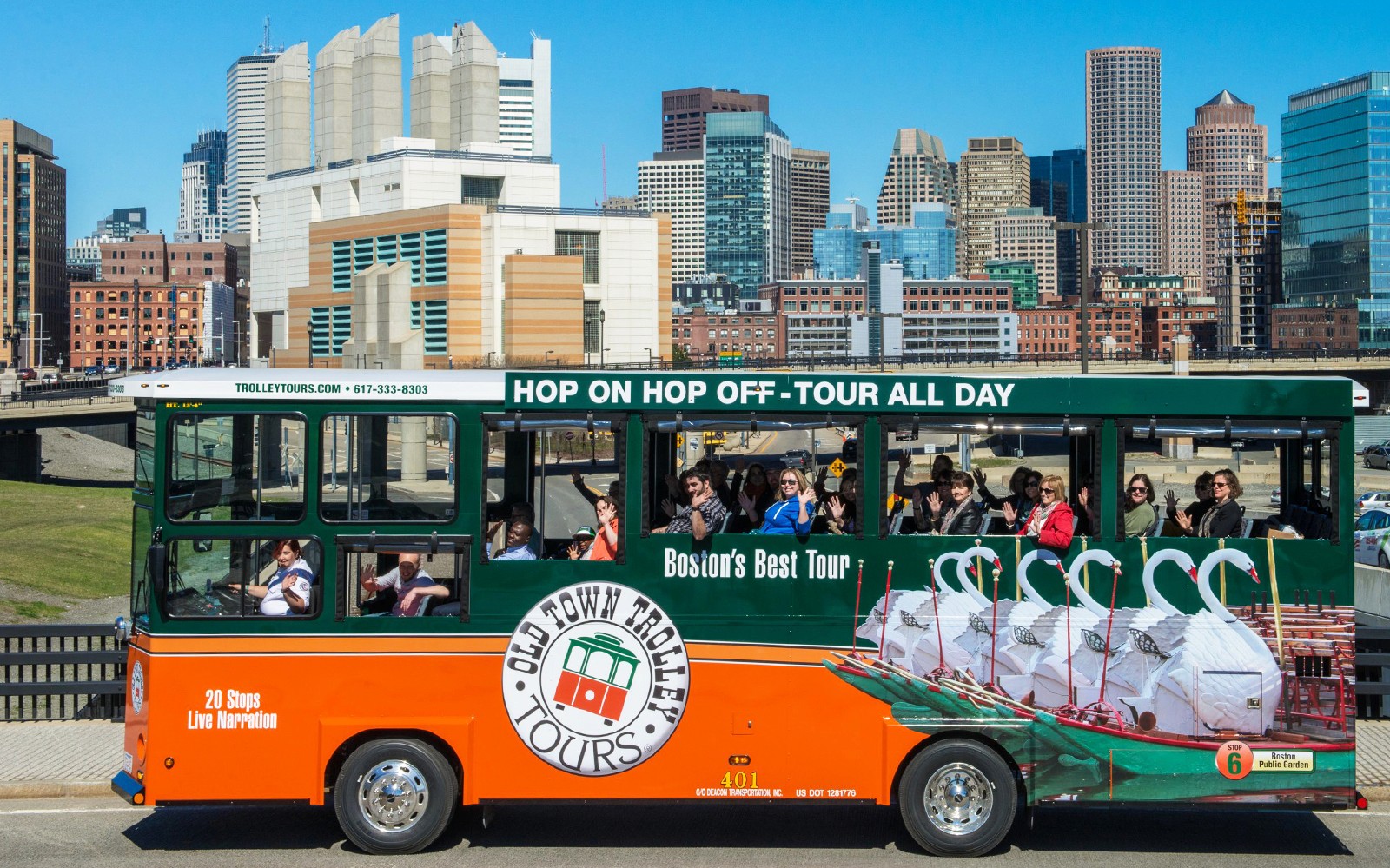 Boston Old Town Trolley with tourists, city skyline in background.