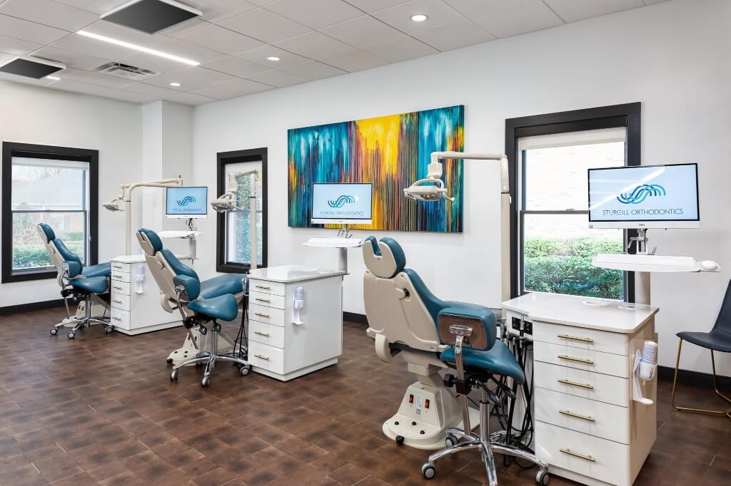 Modern dental office featuring multiple treatment chairs, bright decor, and large windows for natural light.