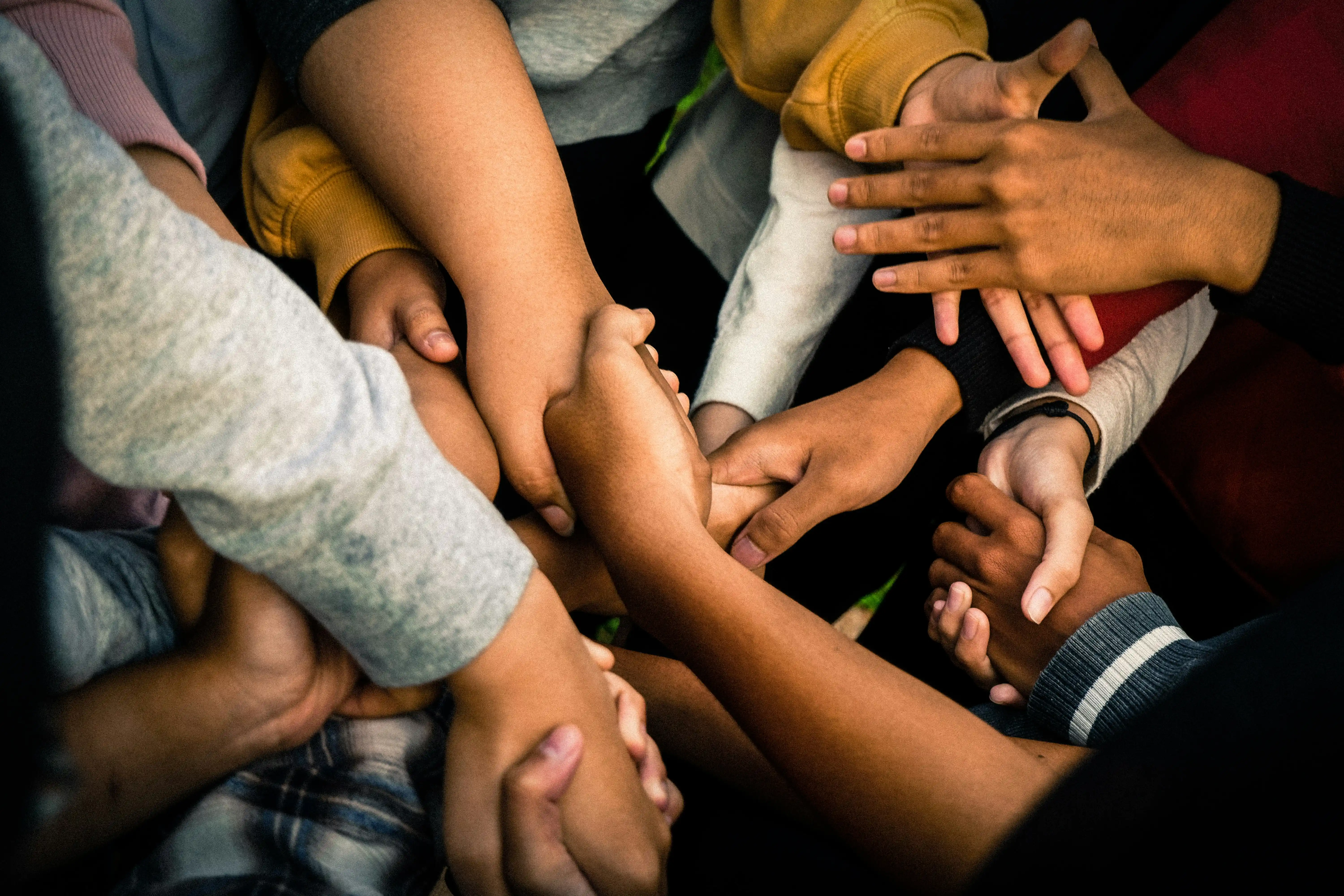 Community members placing hands together in a gesture of support and unity