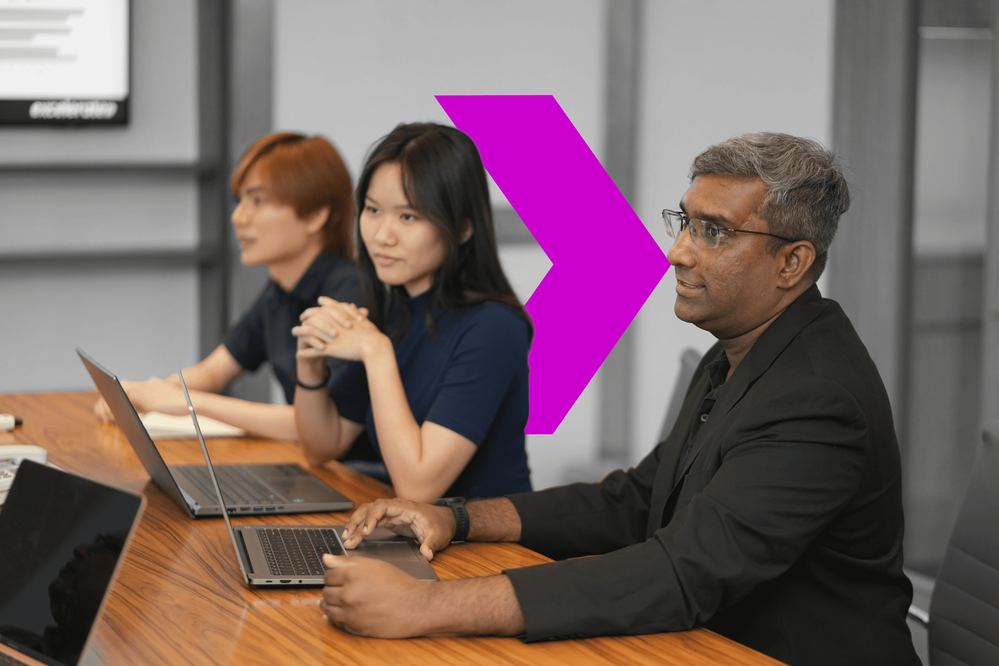 A diverse group of professionals collaborates at a table, each focused on their laptops, embracing AI-driven innovation.
