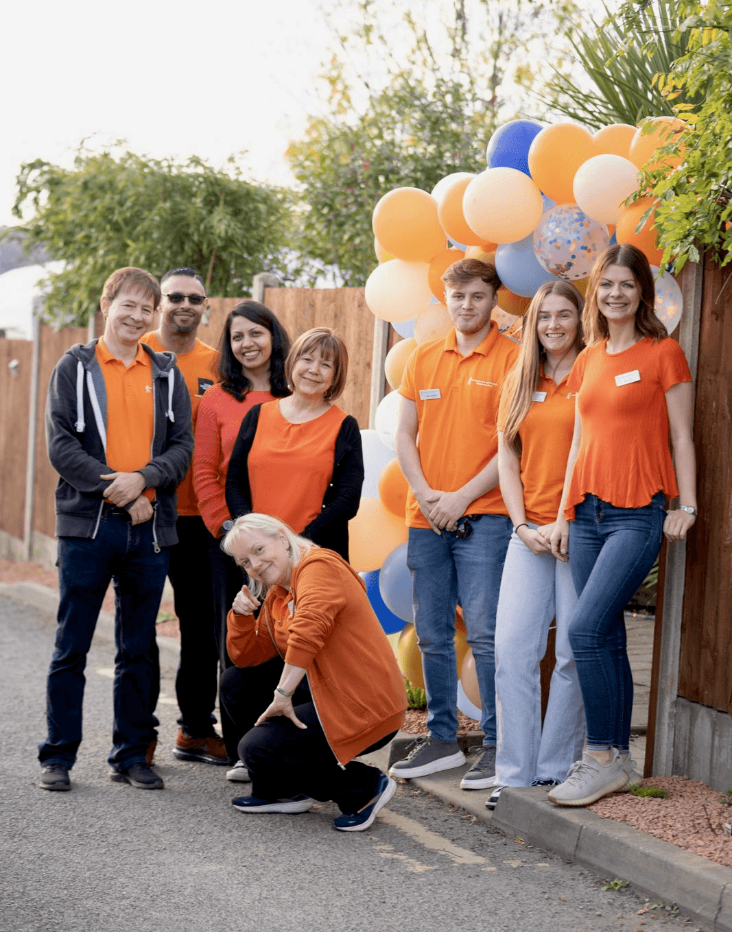 Team photo of our people in their orange shirts posing with balloons. 