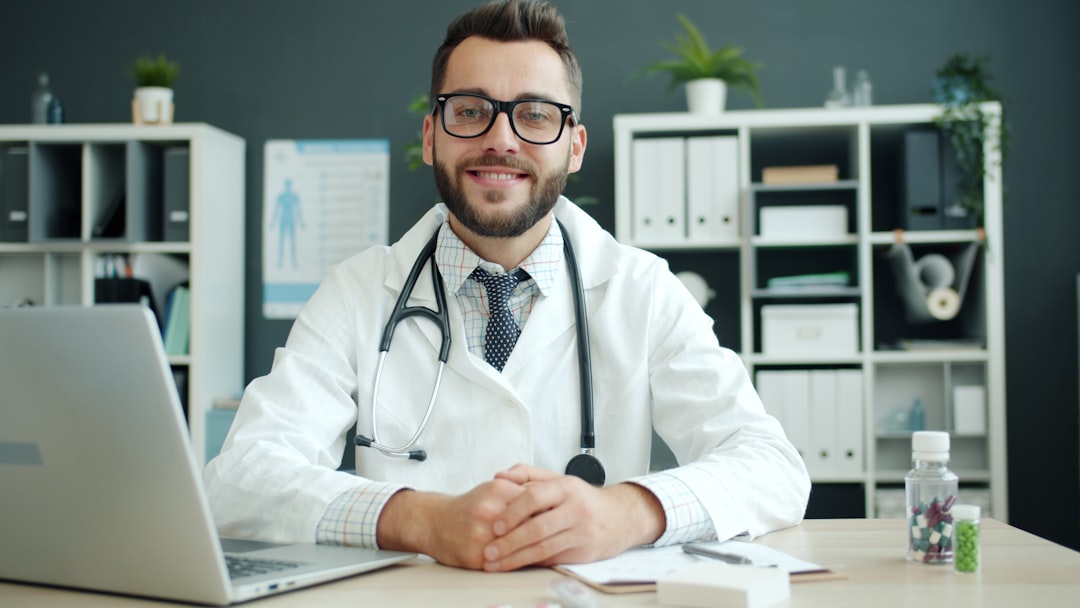 doctor smiling while talking to an elderly patient, bright medical office, minimal computer presence, warm and friendly atmosphere
