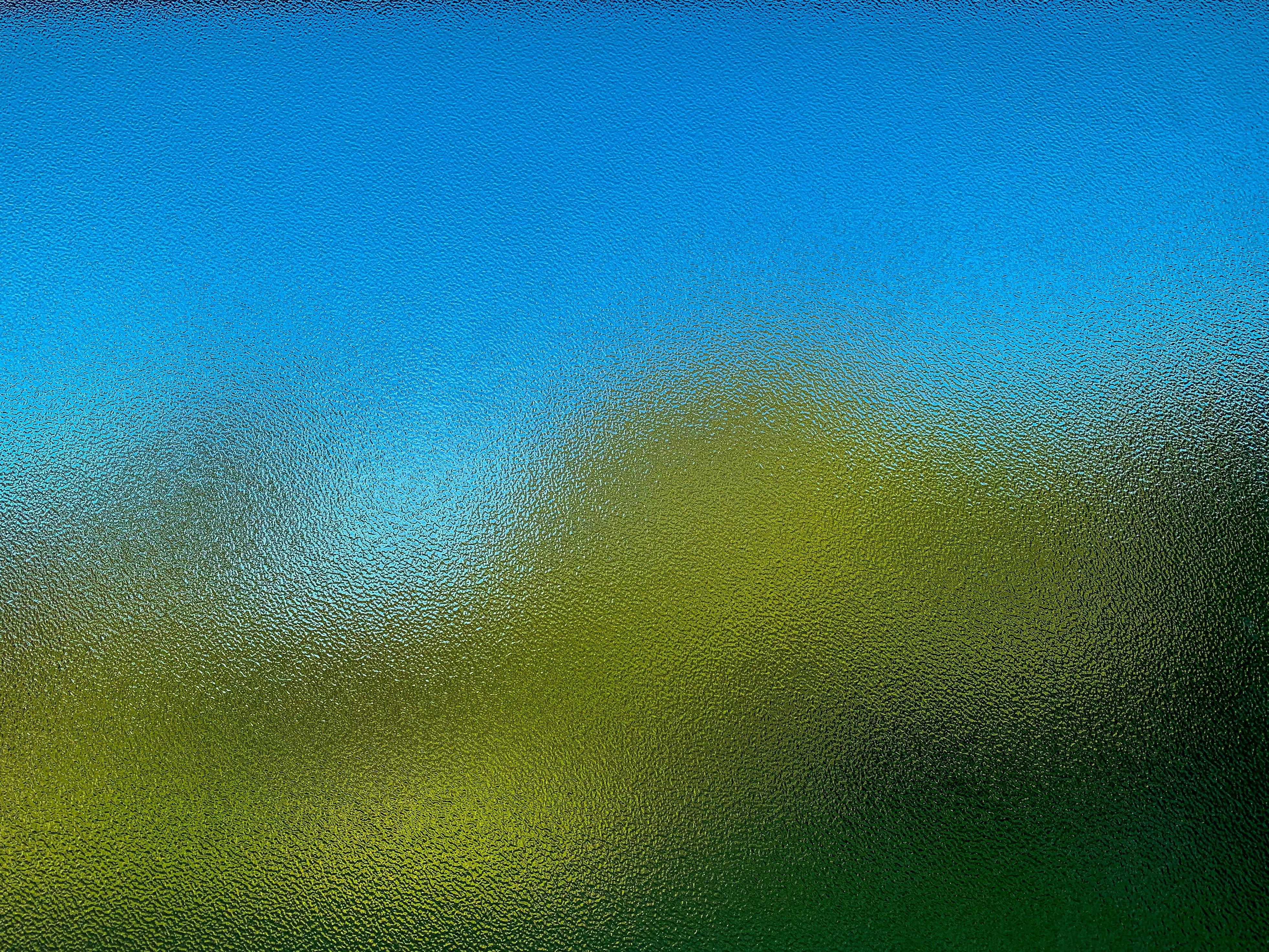 a blurry image of a blue sky and green grass