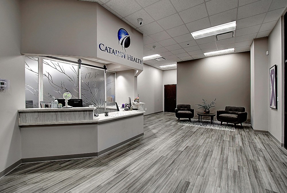 Modern reception area with sleek white finish, gray flooring, and bright overhead lighting.