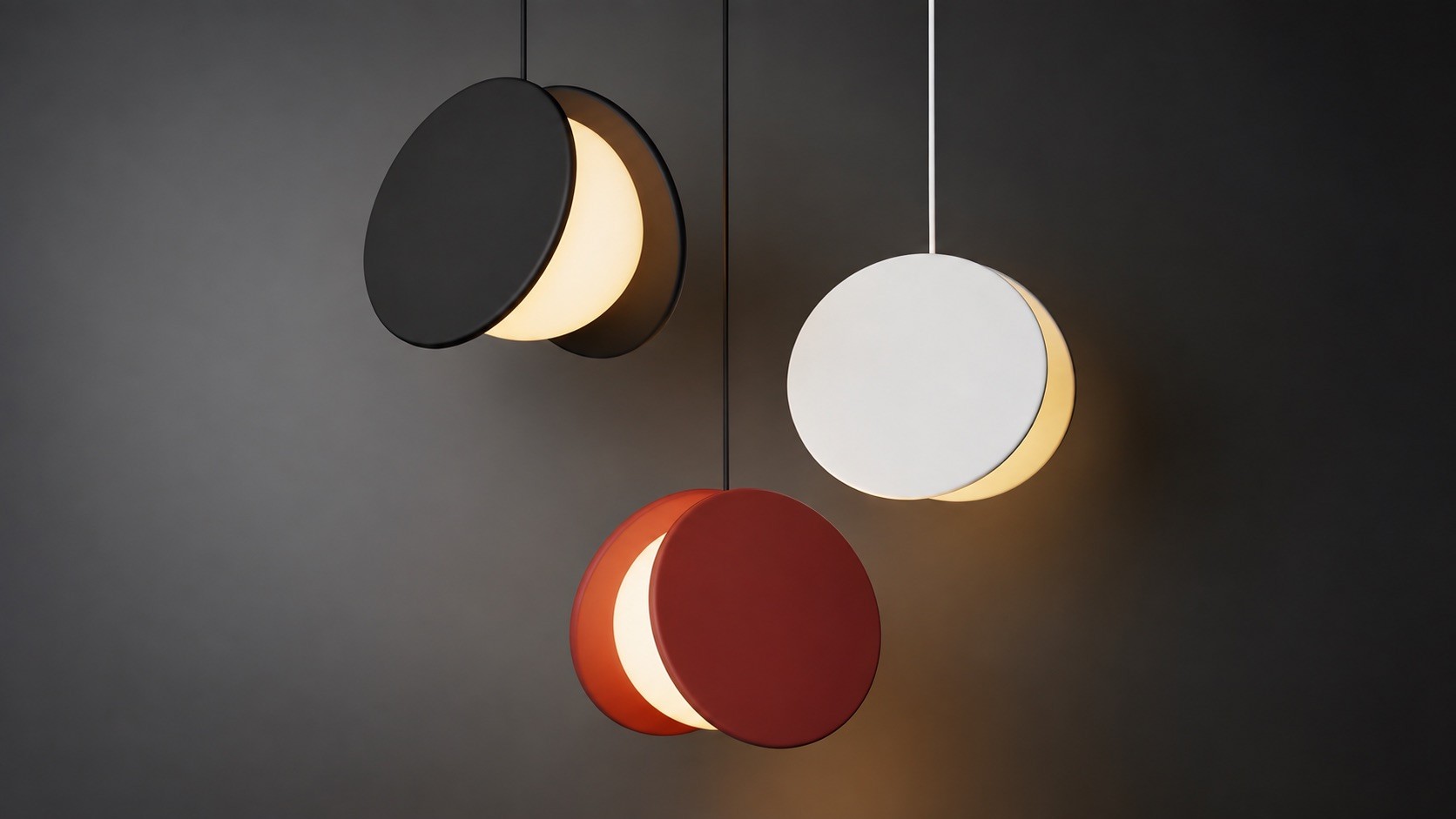 Three pendant lights in black, red and white, each two offset discs around a glowing globe, against a dark gray wall