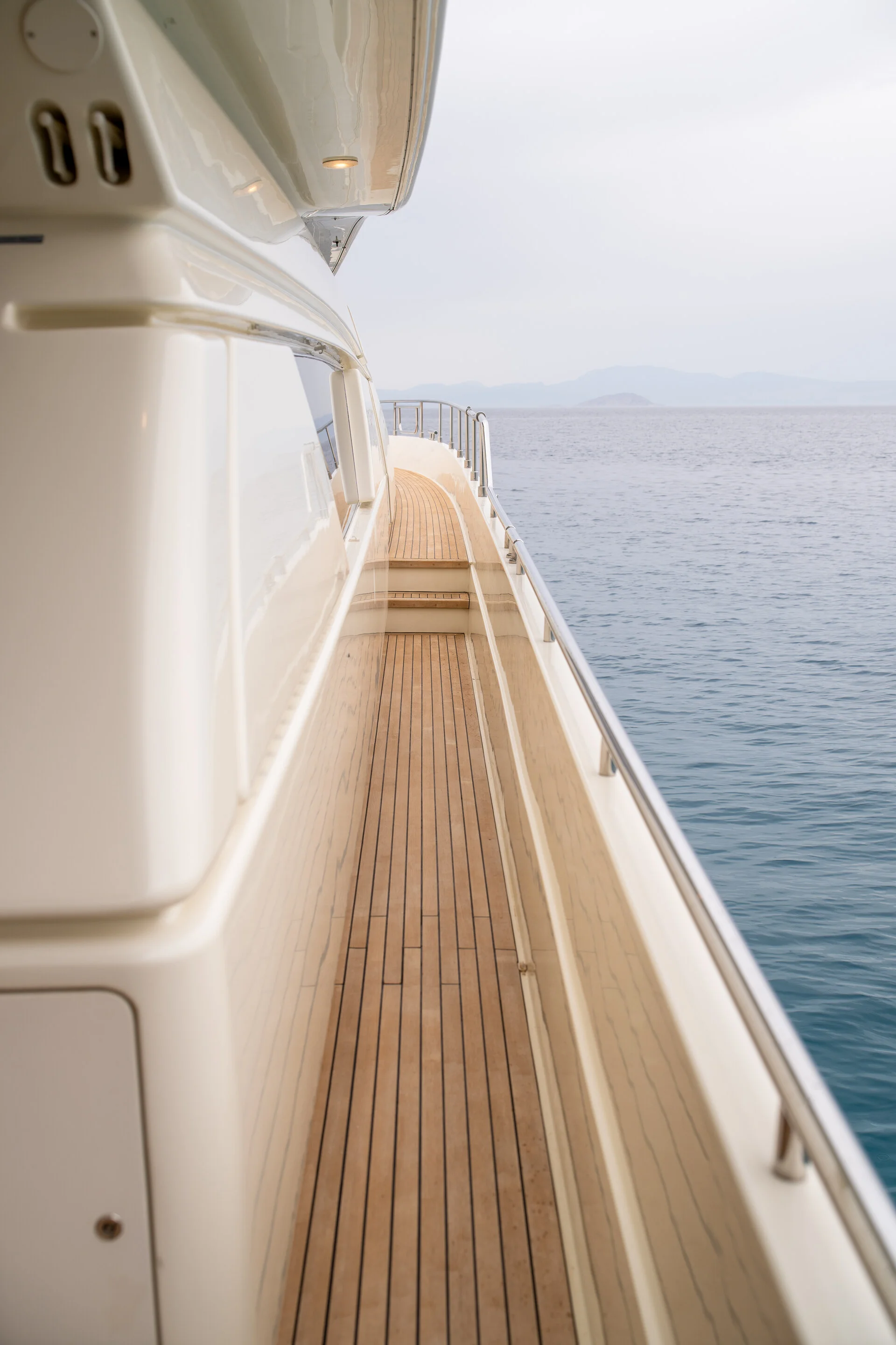 White Rock 36 speedboat with captain at helm cruising calm blue waters near Paros coastline with hills in background.