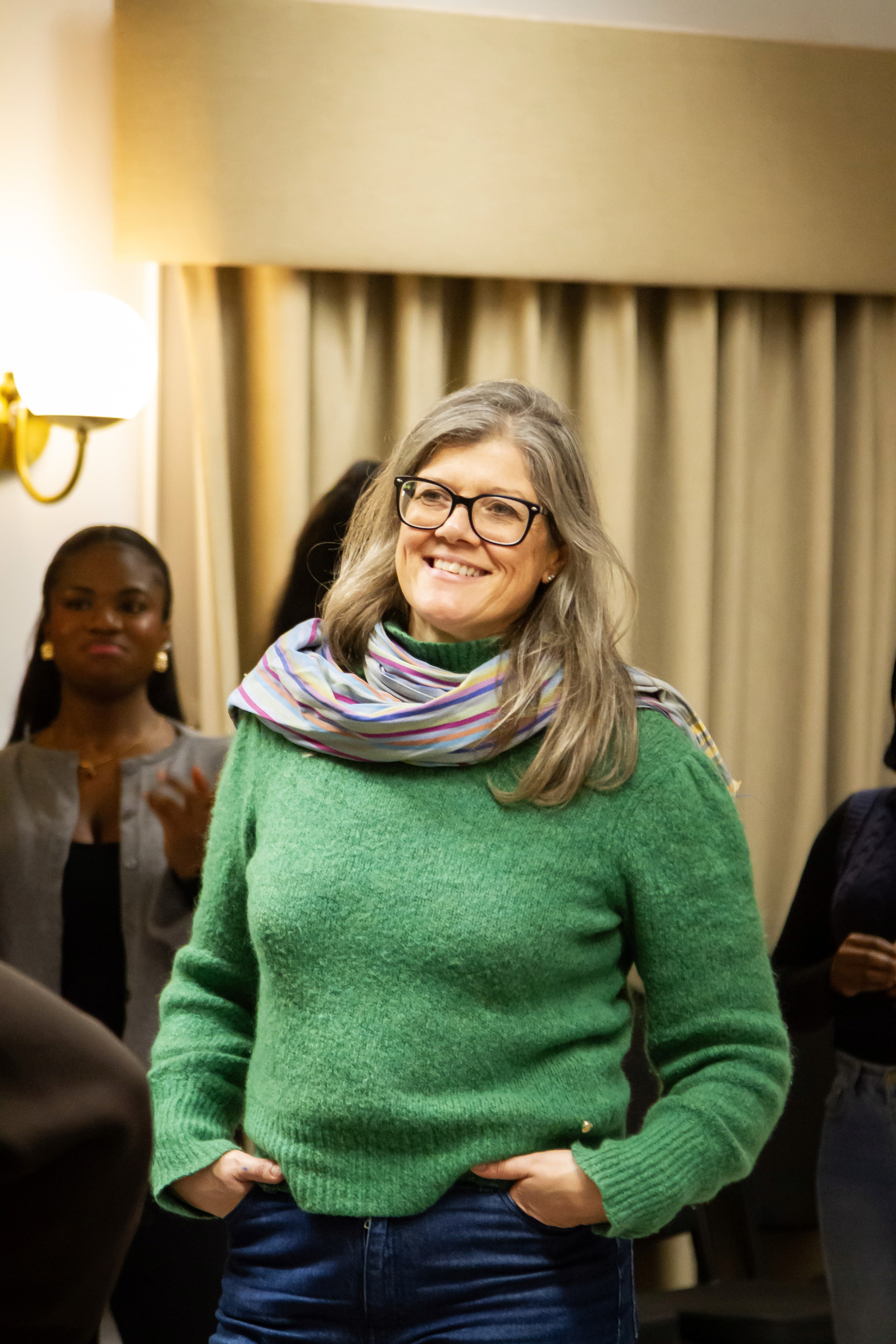 Women smiling with hands tucked in her pocket. 