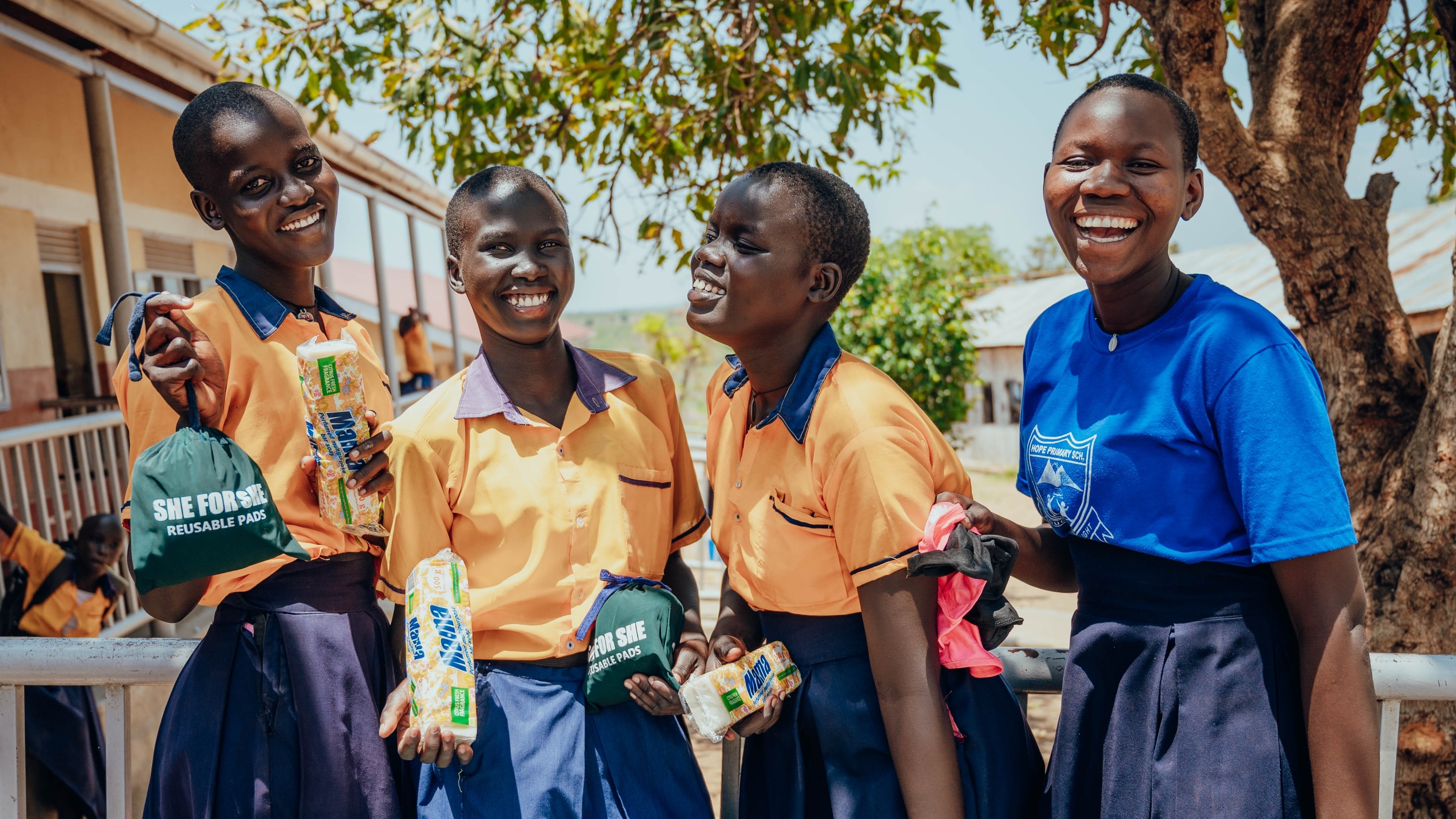 Girls smiling while holding reusable menstrual pads.