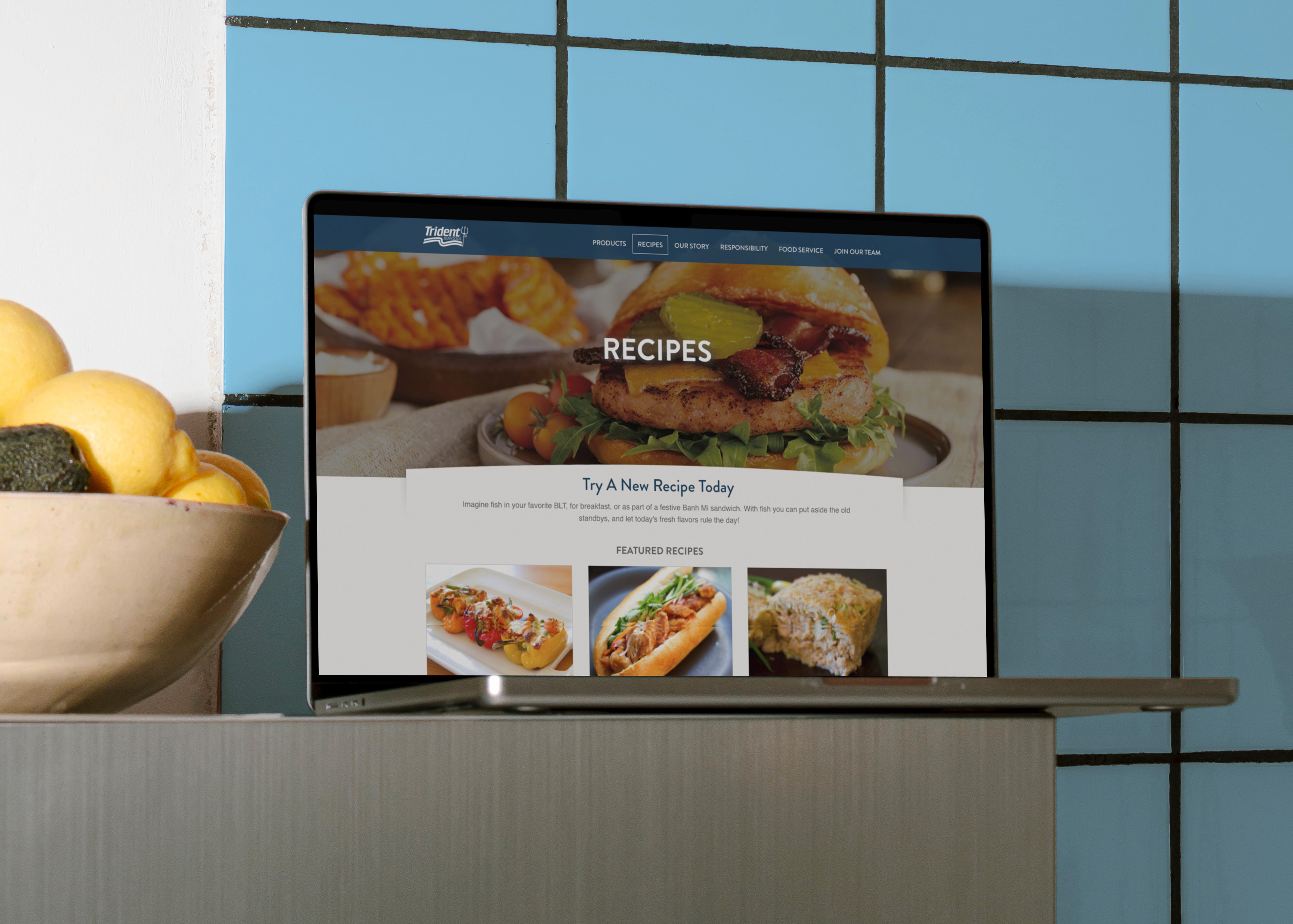 Laptop on counter against a tile wall showing the Trident Website