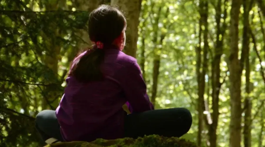 Bambina durante un campo estivo residenziale in natura mentre osserva il bosco, esperienza di crescita personale e educazione outdoor.