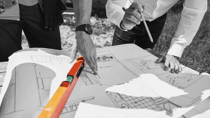 two people working on construction plans resting on a table
