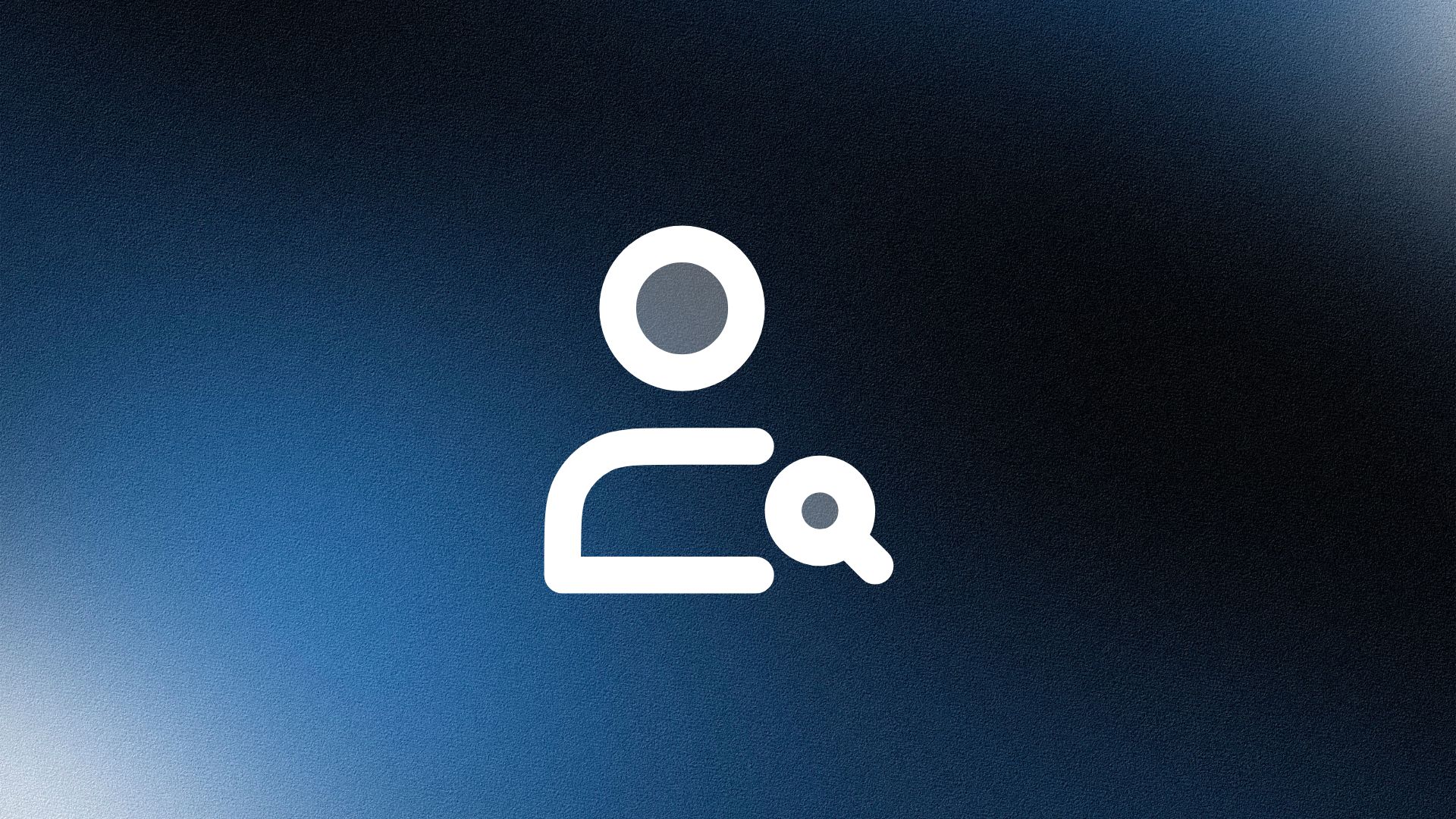 Man wearing a beige cap and dark shirt working on a laptop at a wooden desk with a plant in the background.