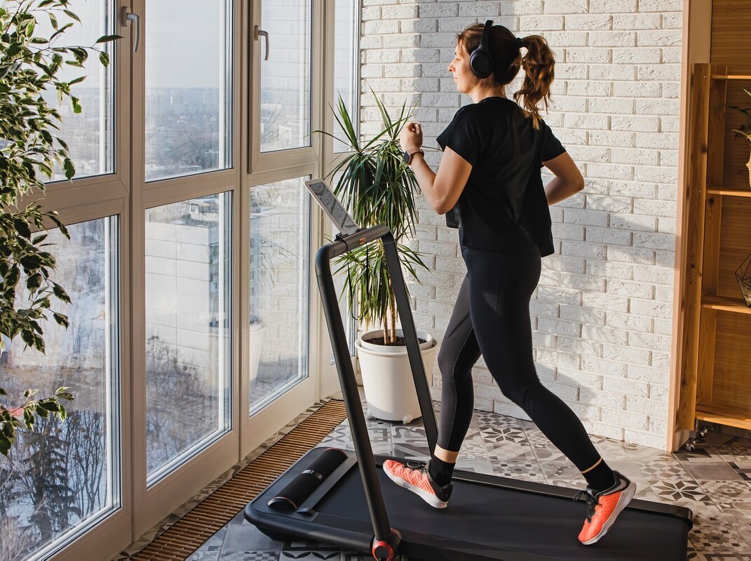 woman trying to lose weight by running on a treadmill at home with a quick session overlooking her view of the city
