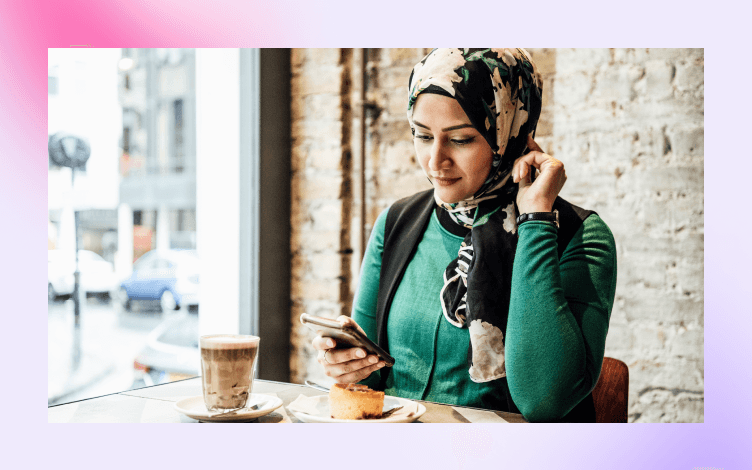 Smiling woman in a hijab reading from her smartphone, reflecting the modern practice of reciting the Quran digitally with respect.