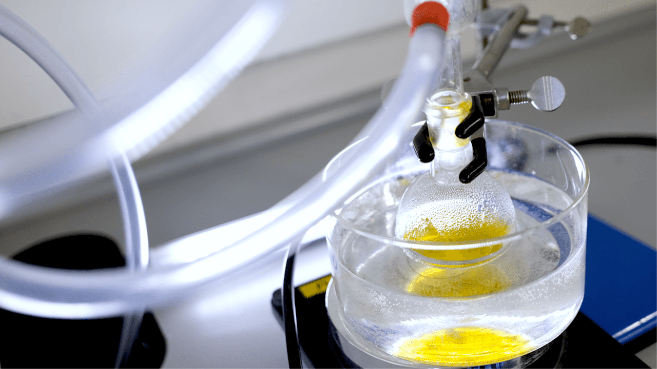 Yellow liquid in a flast, dipped in another flast containing clear liquid.