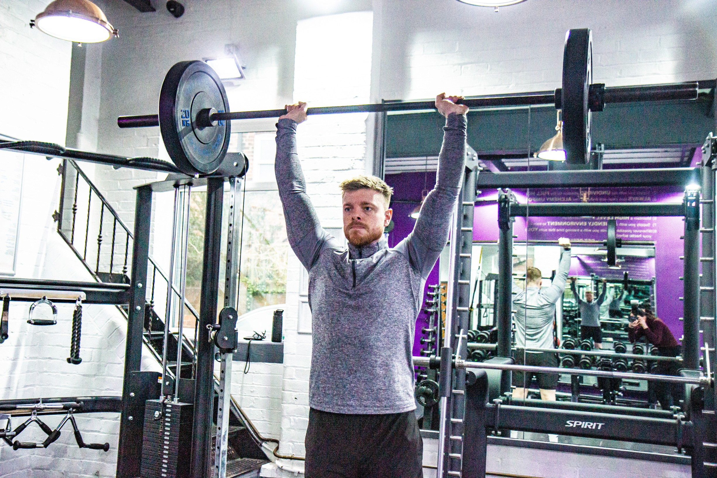 Man doing an overhead press in an indoor gym.