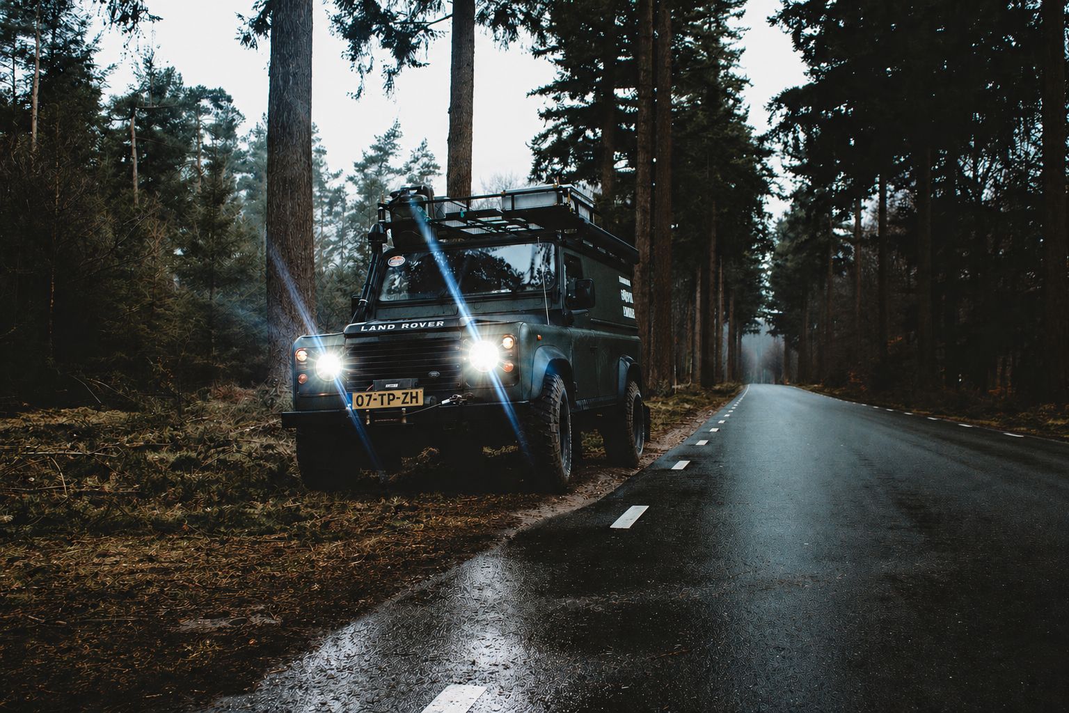 vehicle on side of road with turned on headlights