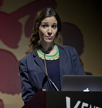 a young woman is giving a speech on a stand
