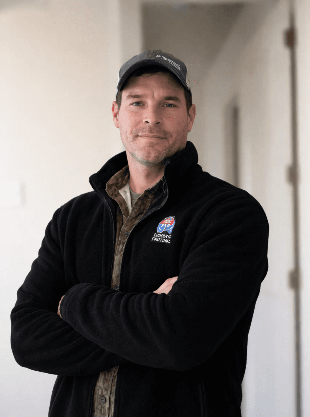 A serene outdoor seating area with two chairs, surrounded by lush greenery and a glassed-in structure.