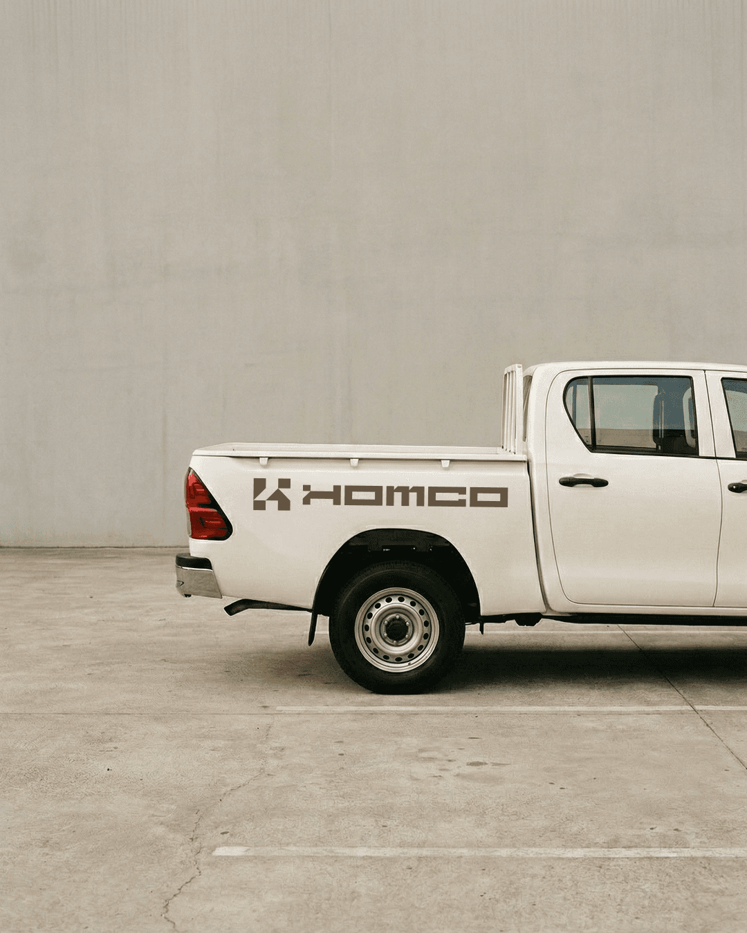 Homco vehicle branding — white pickup truck with Homco logo on tailgate, construction brand asset