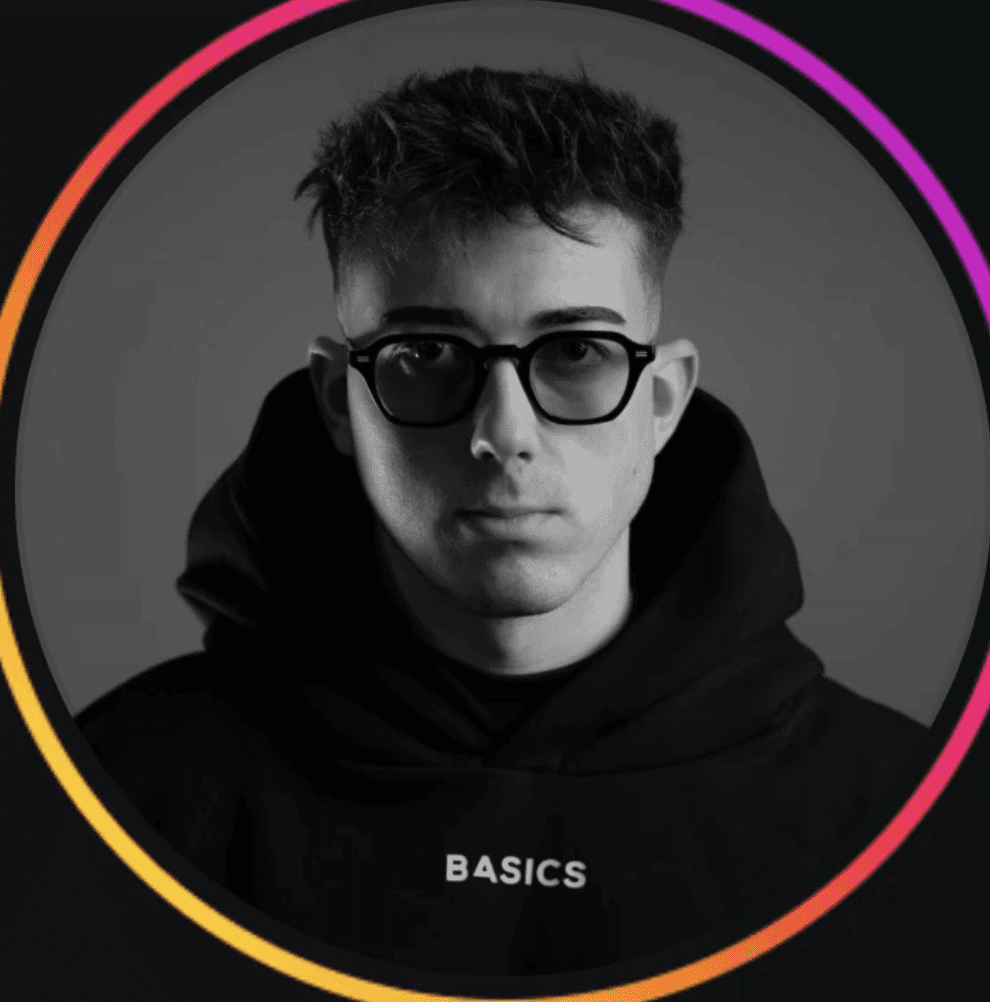 A bearded man in a suit gazes directly at the camera with a confident expression.