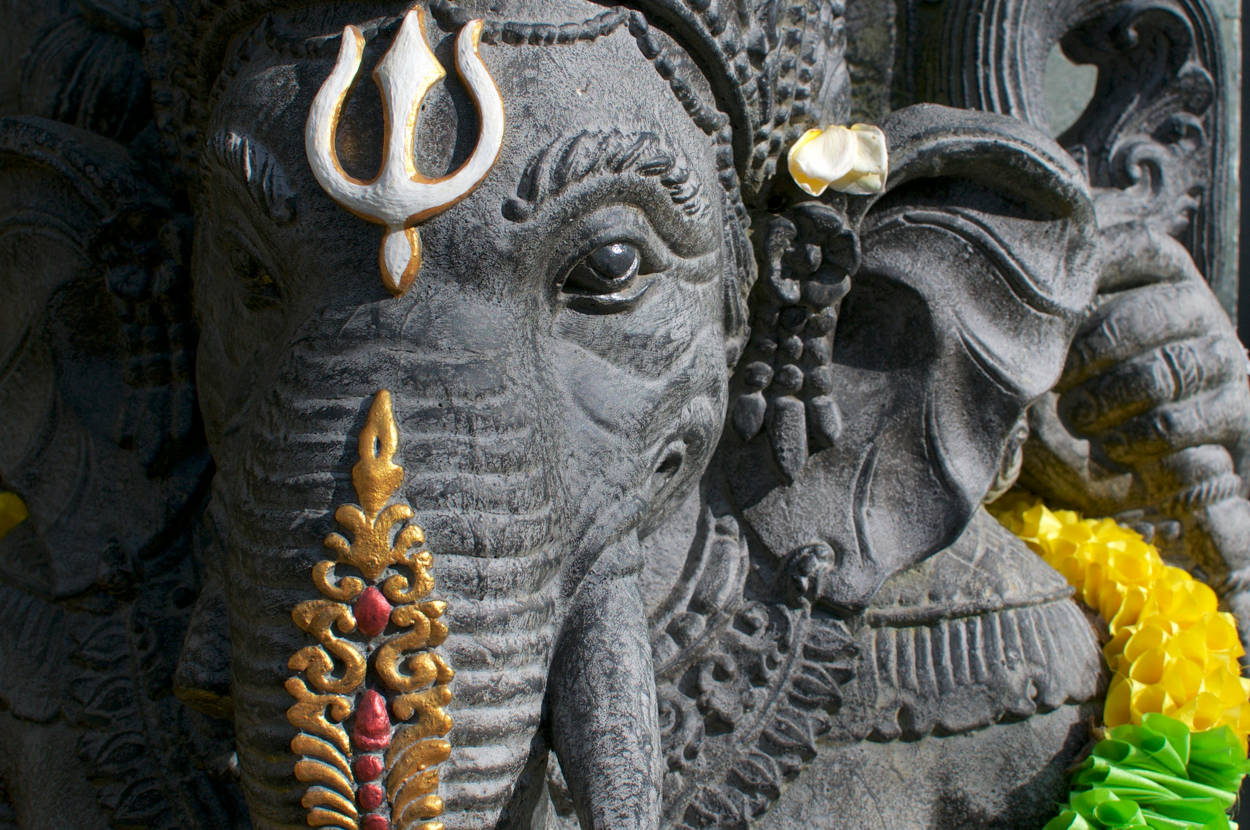 Intricate stone sculpture of Hindu deity Ganesha adorned with flowers, captured in Ubud, Bali