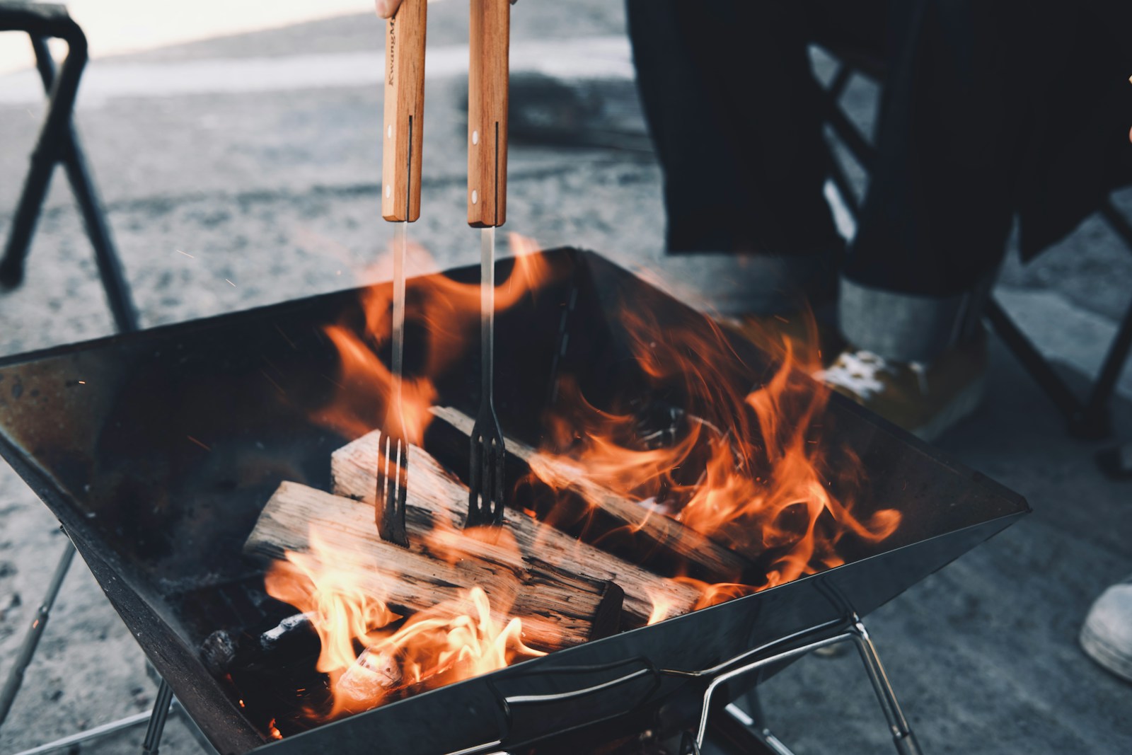 Person grillt Fleisch über offenem Feuer