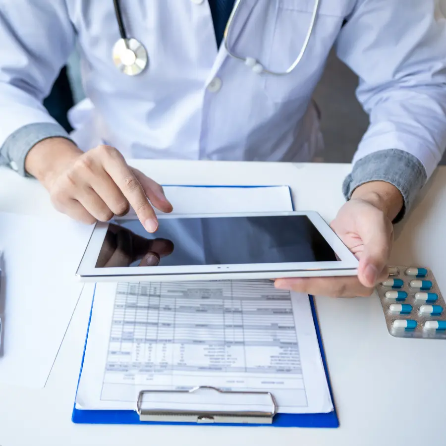 AI for EHR systems helps a doctor review patient records on a digital tablet alongside medical documents and prescriptions