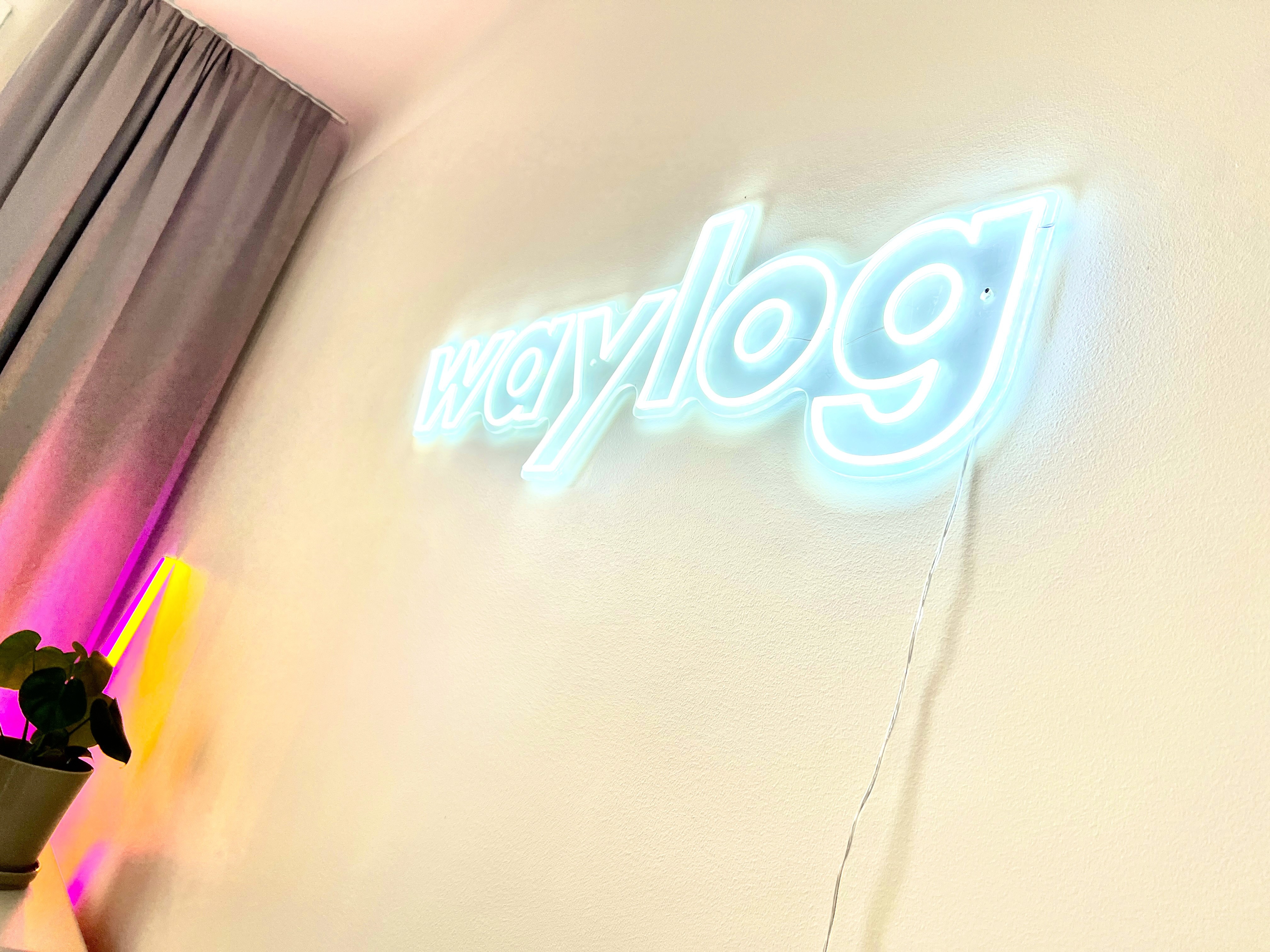 Man with a beard in a dark button-up shirt, smiling while writing in a notebook.