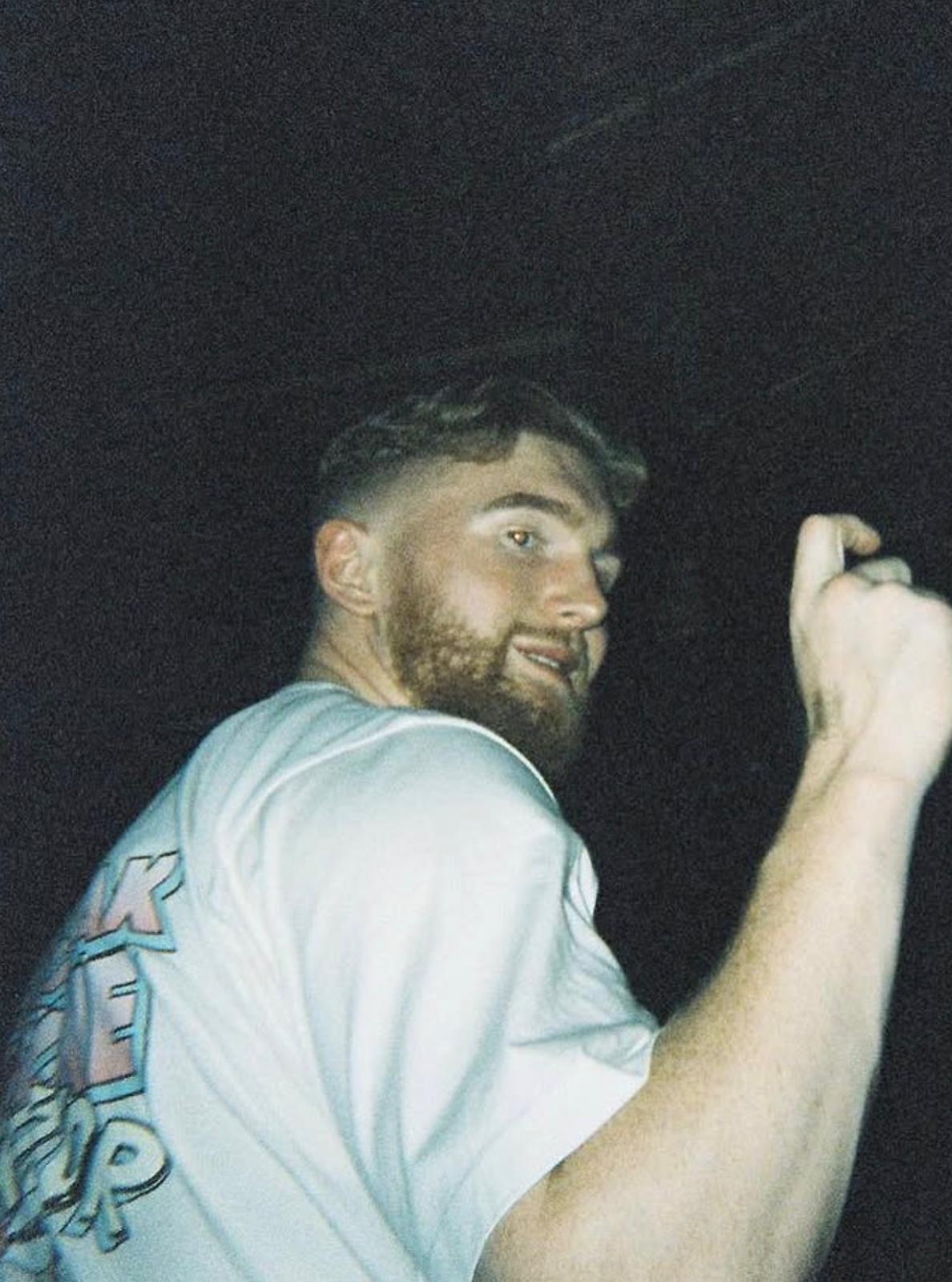 Blonde woman holding a coffee cup, wearing a white t-shirt and light jeans.