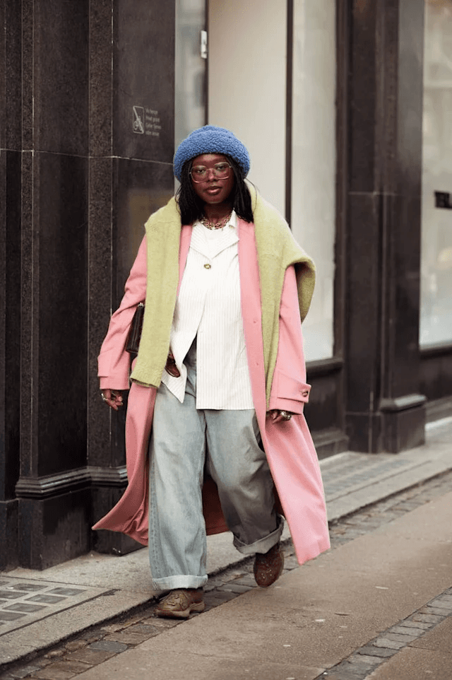 Uma mulher usando roupas em tons pastéis de rosa, azul e verde durante o Copenhagen Fashion Week, exibindo um estilo sofisticado e suave.