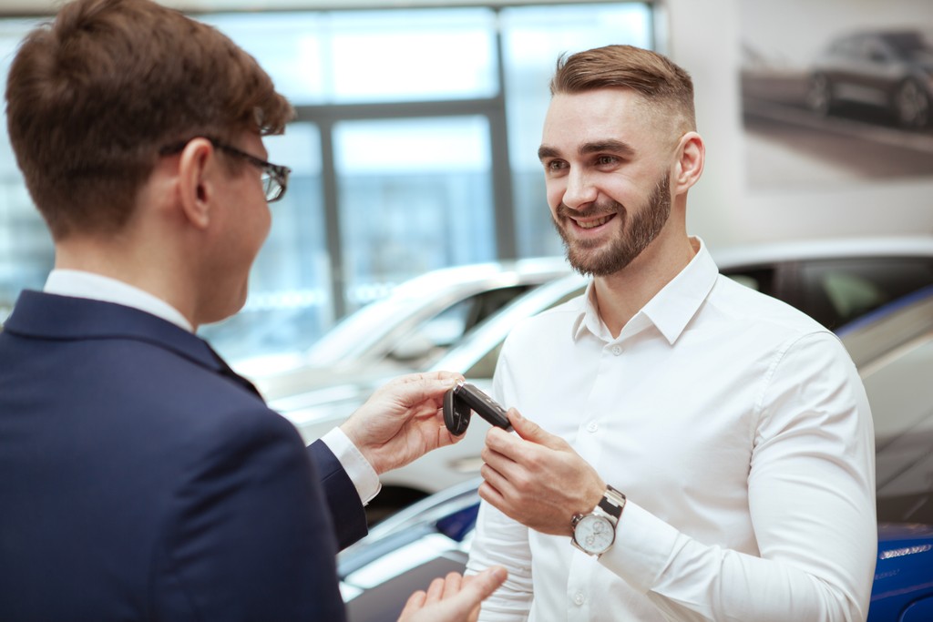 A car salesman giving a vehicle key to a cleint
