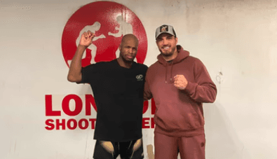 Agron Smakici with an athlete in front of a gym backdrop, celebrating progress and professional training partnerships.