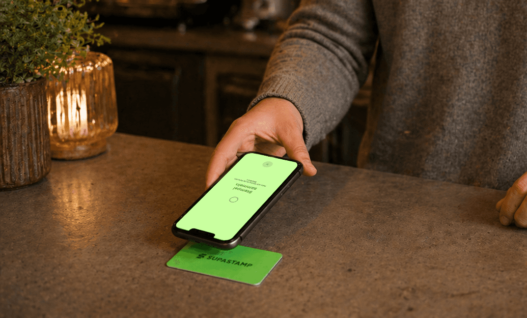 Man holds smartphone against Supa Card in restaurant