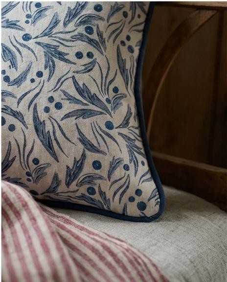A smiling young man with crossed arms, wearing a plaid shirt and white t-shirt, poses against a dark background.