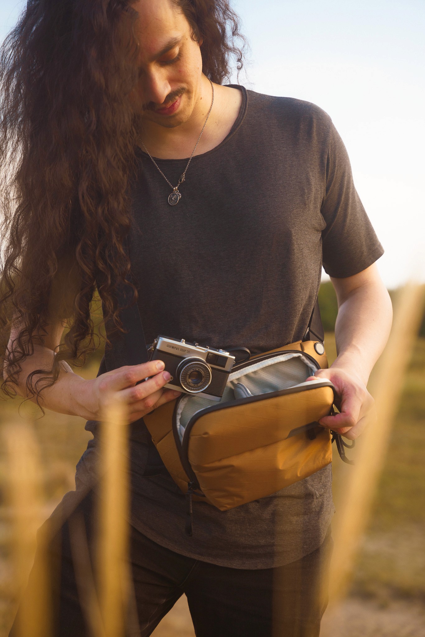 Photographer taking a camera from a Peak Design Coyote sling bag
