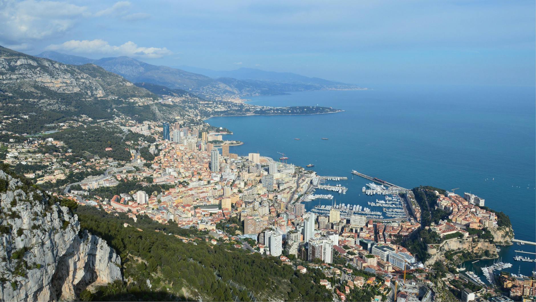Breathtaking aerial view of Monaco's vibrant cityscape, mountains, and blue Mediterranean Sea.