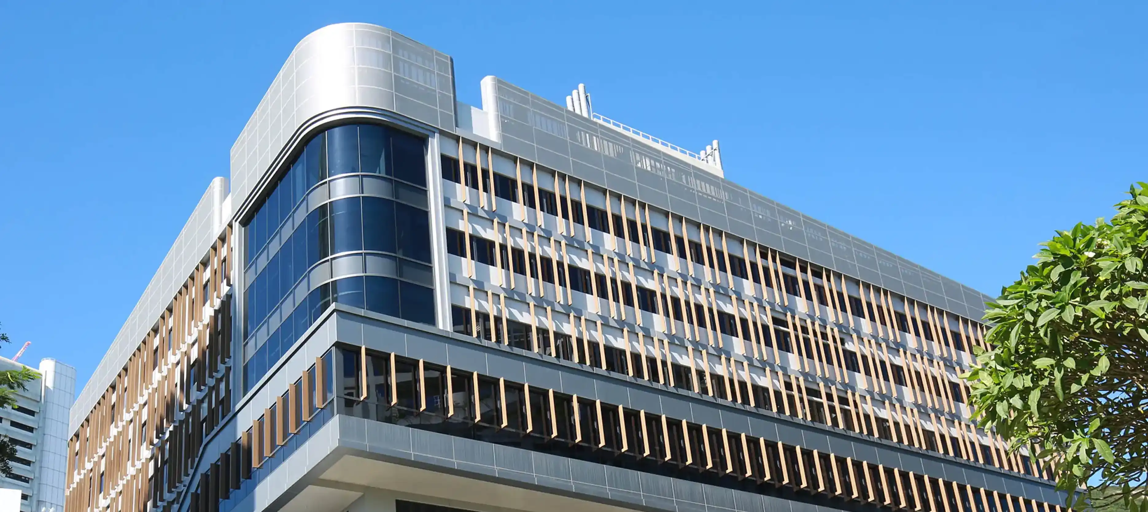 HKU School of Chinese Medicine campus building – modern architecture with curved glass facade under blue sky by Teatime Studio.