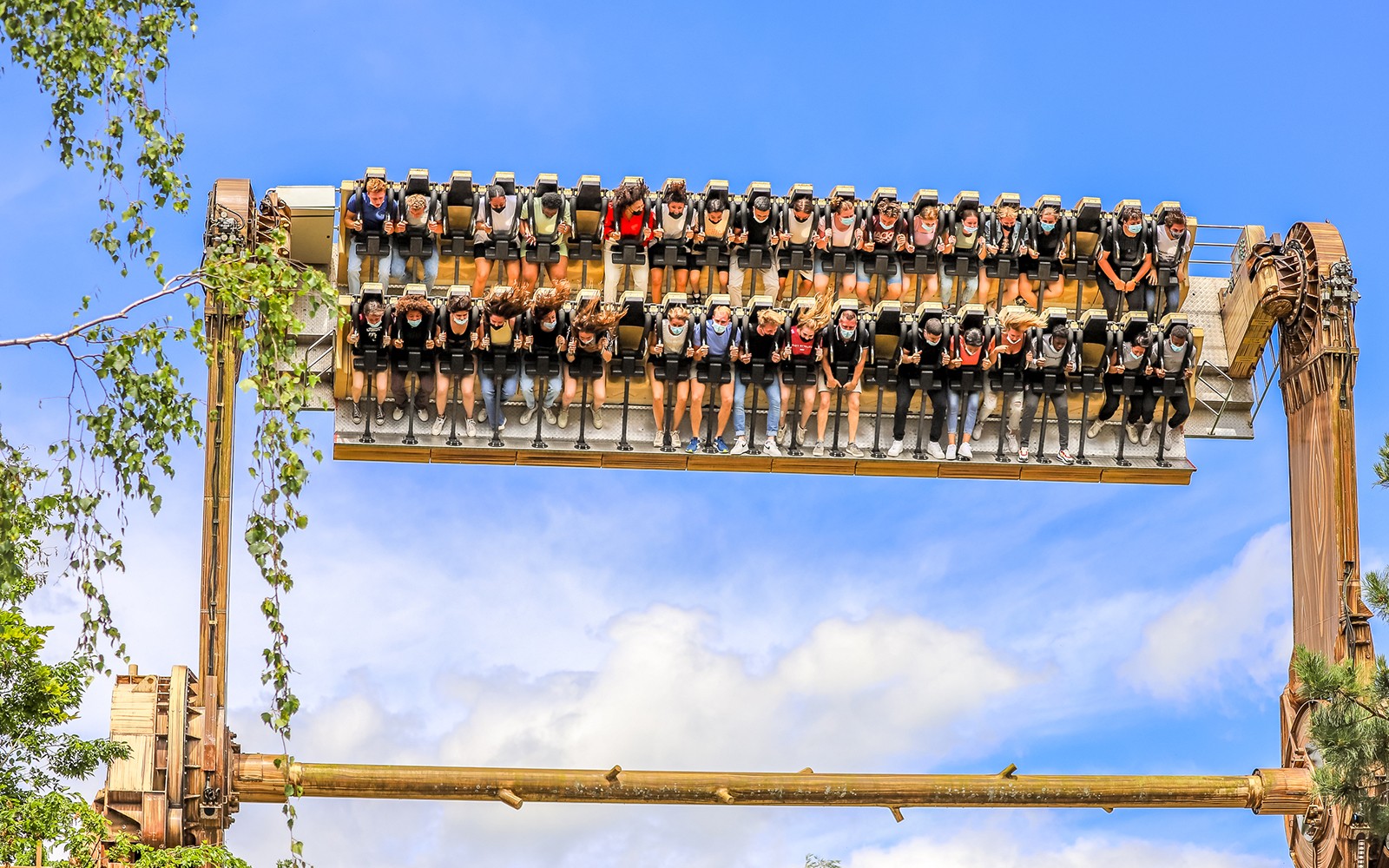 Látogatók egy izgalmas kaland alatt a walibi belgiumi vidámparkban, Wavre-ban, fejjel lefelé, a kék ég ellenében.