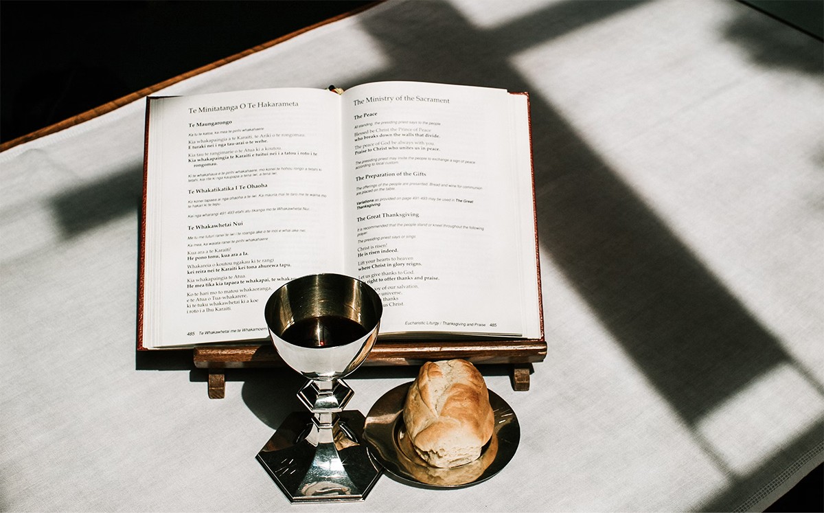 Communion setup with a chalice of wine, a piece of bread, and an open prayer book on a table at Grace Trinity Church.